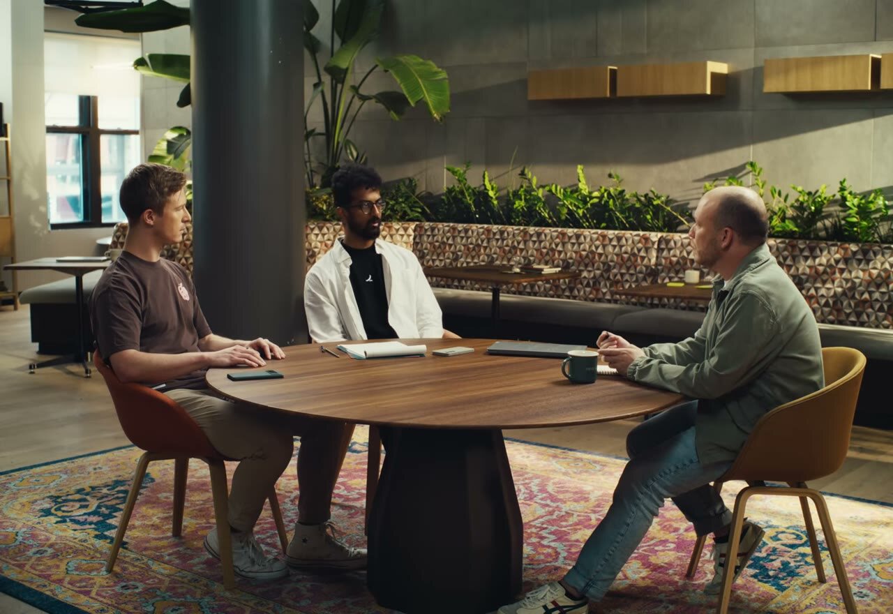 Three engineers in conversation around a round table